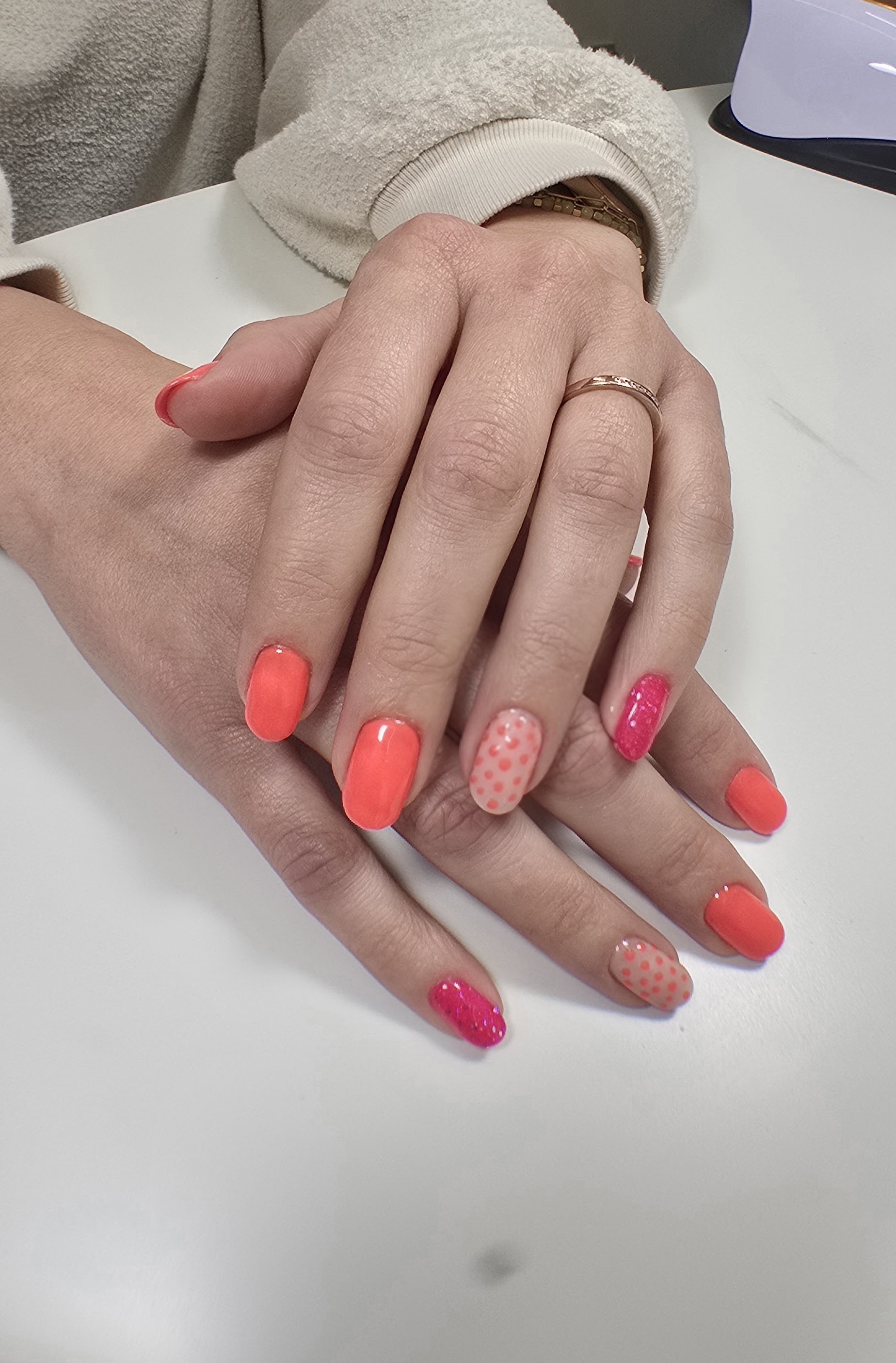 Koraal en roze nagels, één nagel met witte stippen